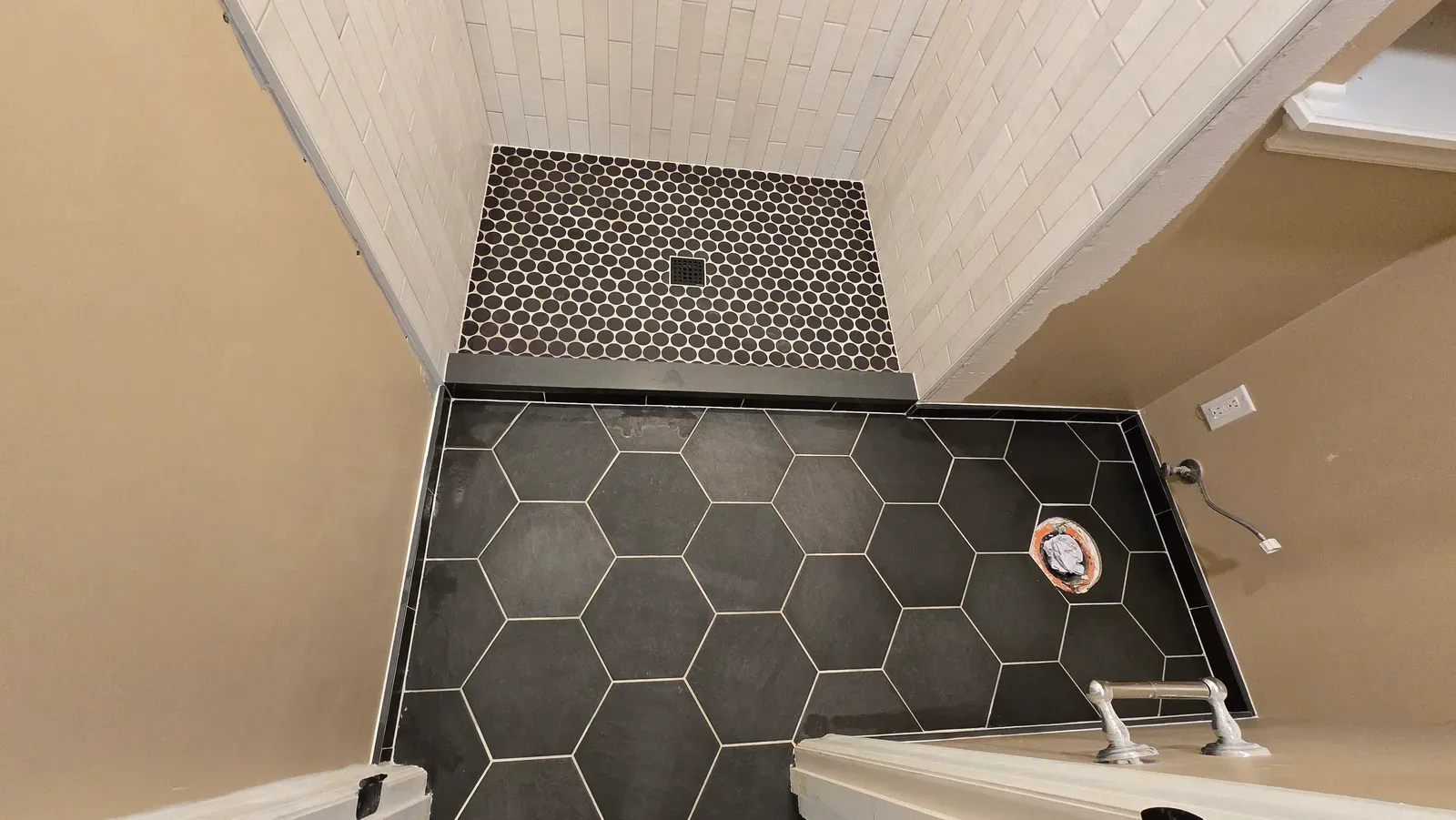 black hex mosaic shower floor with a linear threshold