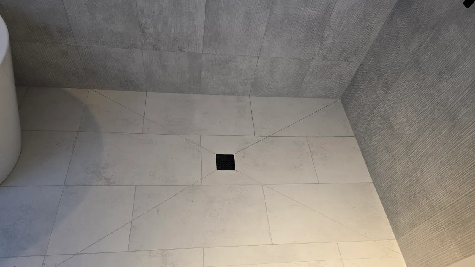 curbless shower floor in large-format tile, sloped to a square drain