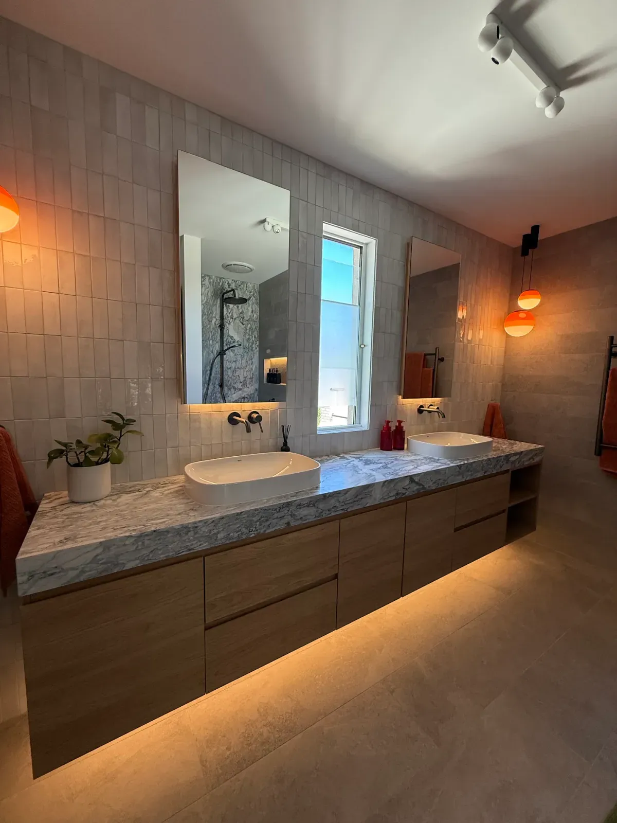 double vanity with a stone top, vessel basins and backlit mirrors