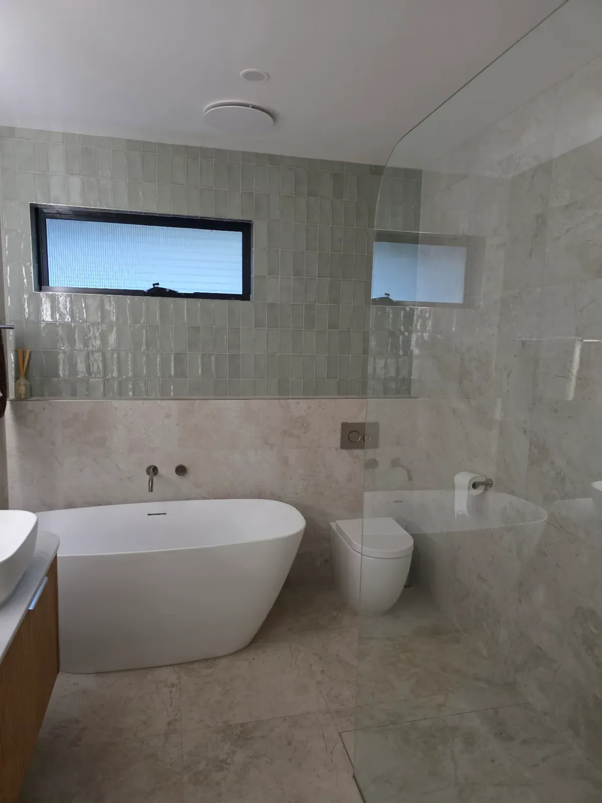 freestanding tub with handmade-look wall tile and a frameless shower