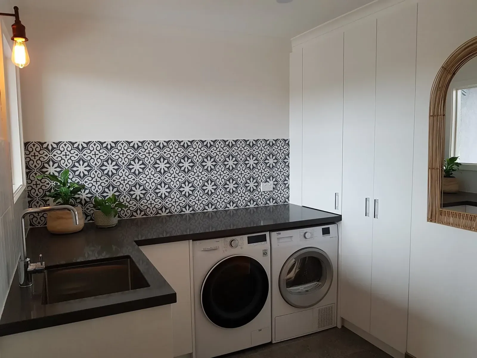 laundry room with a patterned tile backsplash, stone counter and tall storage