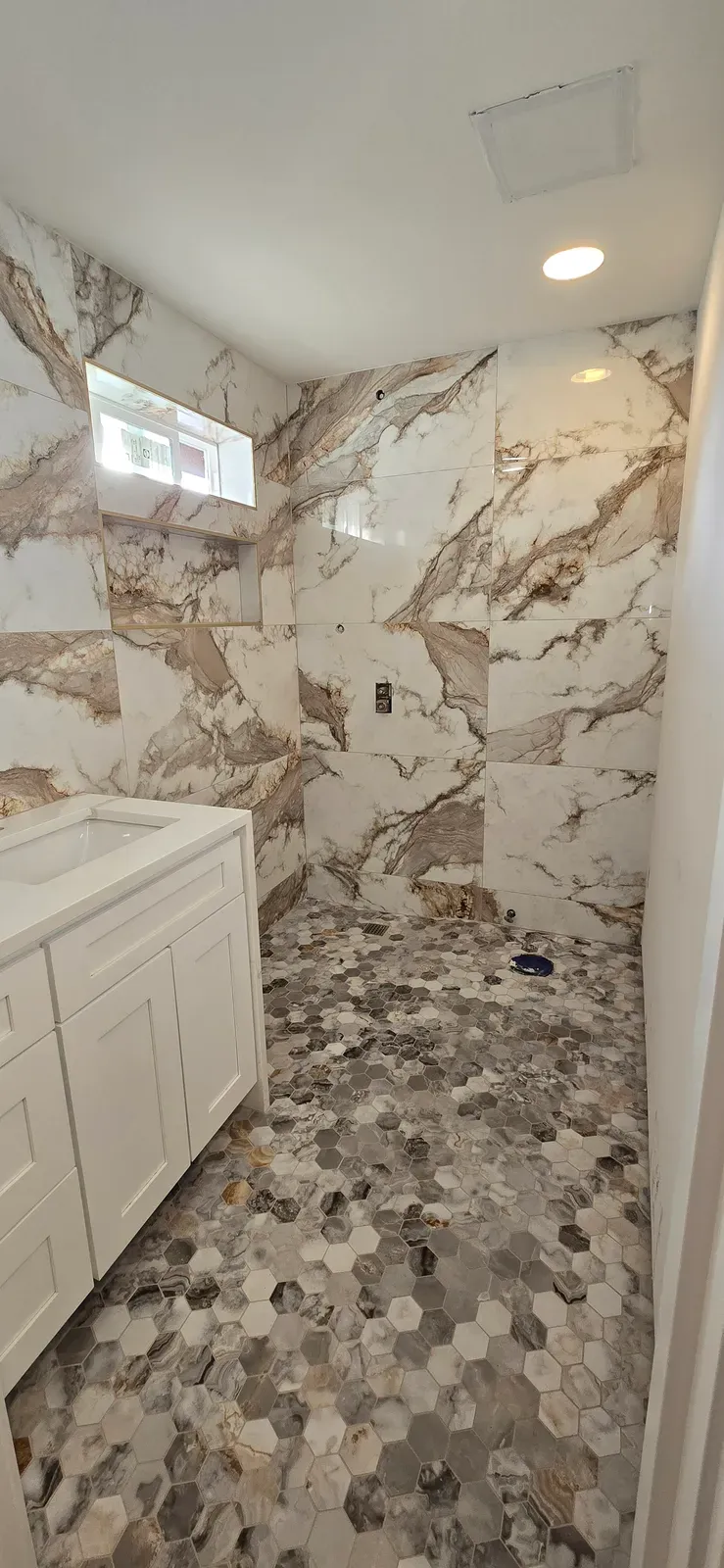 full bathroom in marble-look porcelain with a hex mosaic floor and shaker vanity