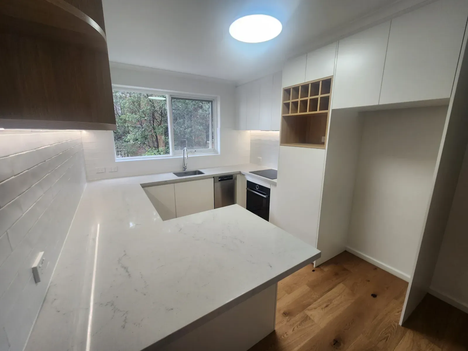 u-shaped kitchen with marble-look quartz, a peninsula and under-cabinet lighting